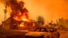 The carcass of a burnt-out car is seen as home burns during the Eaton fire in the Altadena area of Los Angeles county, California on January 8, 2025.