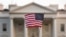 FILE - A flag is waved outside the White House, in Washington, Sept. 5, 2017. The Trump administration is extending a ban on green cards issued outside the United States until the end of 2020 and adding many temporary work visas to the freeze.