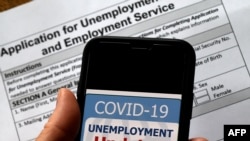 In this illustration photo taken May 08, 2020, a COVID-19 Unemployment Assistance Updates logo is displayed on a smartphone against the backdrop of an application for unemployment benefits, in Arlington, Virginia.