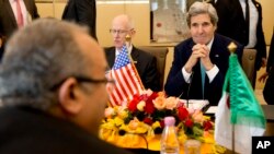 U.S. Secretary of State John Kerry, right, next to U.S. Ambassador to Algeria Henry Ensher, smiles as he listens to Algerian Foreign Minister Ramtane Lamamra, front left across table, Algiers, April 3, 2014.