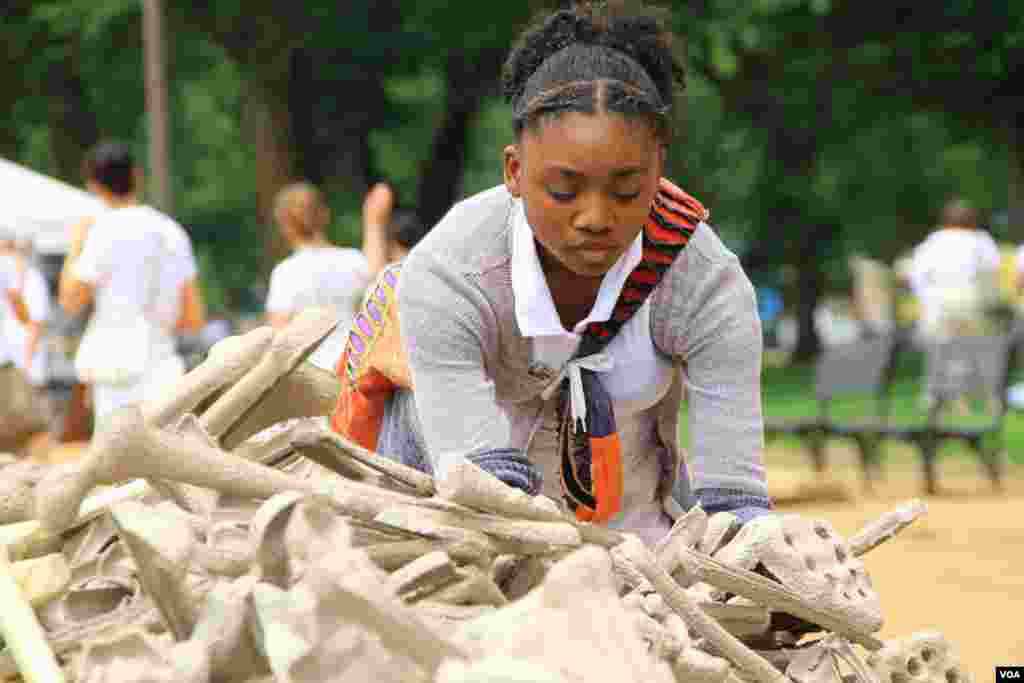 Seorang remaja putri memilih tulang-tulang simbolis untuk ditampilkan dalam instalasi &quot;Sejuta Tulang&quot; di taman National Mall, Washington DC (8/6). (VOA/Jill Craig)