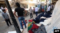 Warga berdiri dekat jenazah-jenazah korban tewas akibat serangan bom barel di kota Aleppo (30/5). (AFP/AMC/Zein al-Rifa)