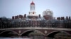 FILE - Rowers paddle down the Charles River past the campus of Harvard University in Cambridge, Mass., March 7, 2017. A federal judge in Boston heard closing arguments Friday in a highly publicized lawsuit alleging that elite Harvard discriminates against
