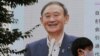 A man walks by a large screen showing Yoshihide Suga, in Tokyo, Sept. 14, 2020.