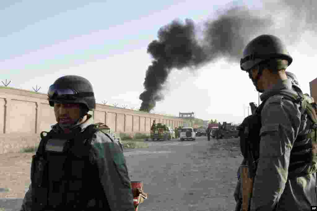 Afghan security force members stand guard near the entrance gate to a NATO compound following a suicide bombing in Kabul, July 2, 2013. 