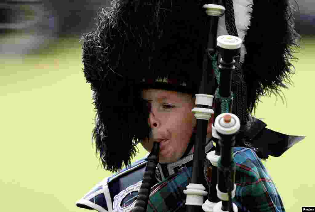 Seorang pemusik muda meniup Piper (seruling Irlandia) di Braemar, Skotlandia, Inggris.
