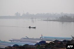 A man steers a boat on a lake amidst high air pollution at the Srilanna National Park in the northern Thai province of Chiang Mai on March 16, 2024. (Photo by Lillian SUWANRUMPHA / AFP)