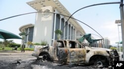 FILE - Burned cars are seen outside a government building, following an election protest in Libreville, Gabon, Sept. 1, 2016.