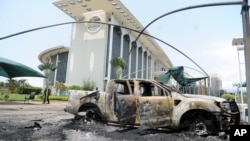 Mobil-mobil yang dibakar di luar sebuah gedung pemerintah, menyusul demonstrasi memprotes hasil pemilu di Libreville, Gabon (1/9). (AP/Joel Bouopda)