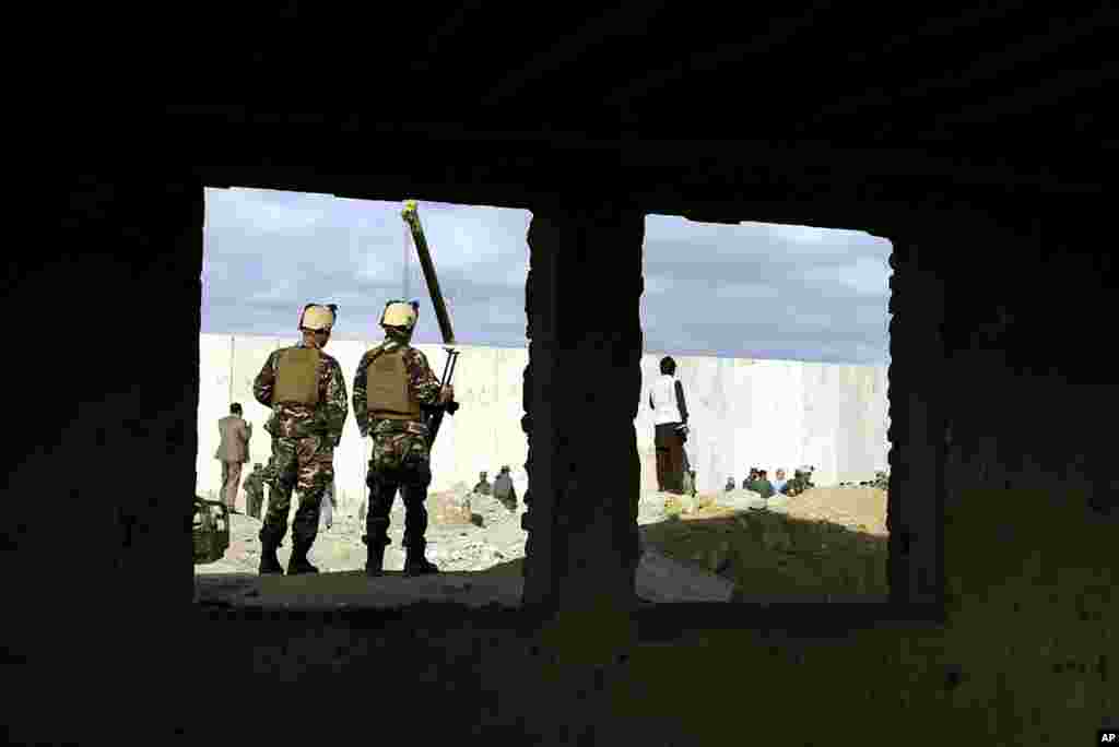 Two Afghan security forces soldiers stand guard at the site of a suicide attack in Kabul, Afghanistan, Oct. 13, 2014.