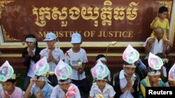 រូបឯកសារ៖ ក្រុមកុមារដែល​ជាកូនៗ​របស់​ស្ត្រី​ដែល​ត្រូវបាន​ចាប់ខ្លួន​ក្នុង​ការប៉ះទង្គិច​ជាមួយ​ប៉ូលិស​ក្នុង​អំឡុងពេល​នៃការបណ្តេញចេញ​ដោយ​បង្ខំនៅ​តំបន់​បឹងកក់​ពាក់​រូបថត​ម្តាយ​នៅលើ​ថ្ងាស នៅក្នុង​ការតវ៉ា​មួយ​នៅមុខ​ក្រសួង​យុត្តិធម៌​ក្នុងរាជធានី​ភ្នំពេញ​កាលពី​ថ្ងៃទី៣១ ខែឧសភា ឆ្នាំ ២០១២។