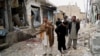 Onlookers stand over the site of a bomb blast outside a Shiite Muslim mosque in Hangu, February 1, 2013.