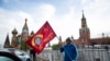 A man poses for a photo with a red flag in front of the closed Red Square during the 75th anniversary of the Nazi defeat in World War II in Moscow, Russia, May 9, 2020.