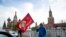 A man poses for a photo with a red flag in front of the closed Red Square during the 75th anniversary of the Nazi defeat in World War II in Moscow, Russia, May 9, 2020.