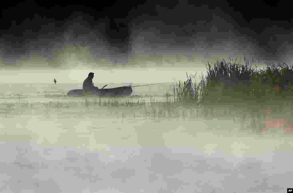 បុរស​ម្នាក់​ស្ទួច​ត្រី​ពី​ទូក​របស់​ខ្លួន អំឡុងពេល​មាន​អ័ព្ទ​ធ្លាក់​លើ​បឹង​មួយ​នៅ​ជាយ​ក្រុង Logoisk ចម្ងាយ ៤០ គីឡូម៉ែត្រ ភាគ​ខាង​ជើង​ក្រុង Minsk ប្រទេស​បេឡារូស។