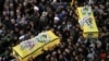 Shi'ite militant group Hezbollah's fighters and supporters carry the coffins of a father and son, wrapped in a Hezbollah flag, during their funeral procession in the southern town of Ghaziyeh, Lebanon, Jan. 21, 2015.