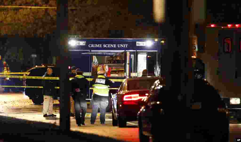 Law enforcement officials investigate at the scene of a shooting in Urbandale, Iowa. Two Des Moines area police officers were shot to death early in the morning in ambush-style attacks while they were sitting in their patrol cars.