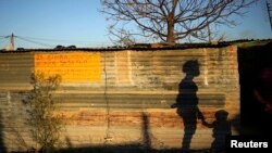 The shadows of a mother and child are cast on a shack in Marikana's Nkaneng township in Rustenburg, 100 km (62 miles) northwest of Johannesburg, August 15, 2013.