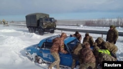 资料照片：乌克兰军人在敖德萨地区帮助一辆陷在大雪中的汽车脱险。(2023年11月28日）