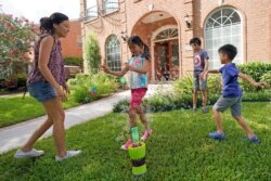 FILE - Vicky Li Yip sets up a bubble machine for her children, left to right, Kelsey, 8, Toby, 10 and Jesse, 5, outside their home, July 10, 2020, in Houston, Texas.