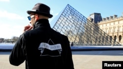 French artist JR works in the courtyard of the Louvre Museum near the glass pyramid designed by Ieoh Ming Pei as the Louvre Museum celebrates the 30th anniversary of its glass pyramid in Paris, France, March 26, 2019. 