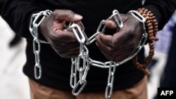 FILE - An African migrant with his hands chained takes part in a march toward the offices of the European Union during a demonstration on Dec. 2, 2017, in central Athens, protesting against the slavery of migrants in Libya.