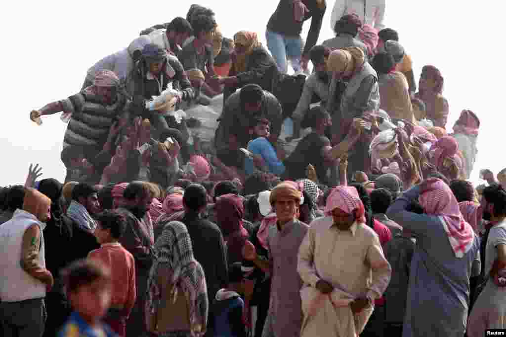 Warga Irak yang mengungsi dari kota Mosul, dan warga Suriah yang mengungsi dari Deir al-Zor yang dikuasai ISIS, membeli makanan dan air di Hasaka, Suriah.