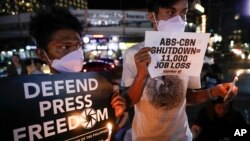 Protesters light candles while they hold banners, during a rally in metropolitan Manila, Philippines, Monday, Feb. 10, 2020. The Philippine government's chief lawyer asked the Supreme Court on Monday to shut down the country's largest TV network,…