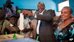 Kenyan Presidential candidate Uhuru Kenyatta casts his vote, accompanied by his wife Margaret Wanjiru Gakuo (R), at the Mutomo primary school near Gatundu, north of Nairobi, in Kenya, March 4, 2013.