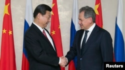 资料照：中国领导人习近平在访问莫斯科期间与时任俄罗斯国防部长、现任俄罗斯联邦安全会议秘书、前国防部长谢尔盖·绍伊古（Sergei Shoigu）（右）握手。(2013年3月23日)
