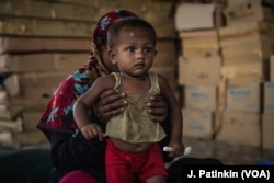 A Rohingya refugee mother holds her recovering baby who has received treatment for malnutrition at an Action Against Hunger clinic in Ukhiya, Bangladesh, April 18, 2018.