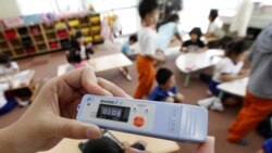 A teacher measures the radiation level at an elementary school outside the 20-kilometer evacuation zone around the Fukushima nuclear power plant