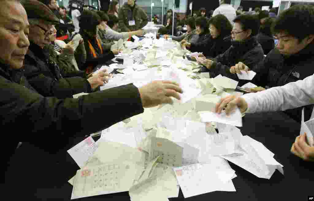 Petugas Komisi Pemilihan Umum Korea Selatan memilah-milah kertas suara pada penghitungan suara di Seoul (19/12). (AP/Ahn Young-joon)