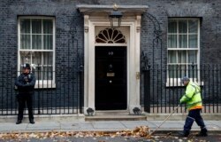 FILE - A street cleaner clears fall leaves from the front of 10 Downing Street, London, Britain, Nov. 6, 2019.