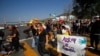FILE - Migrants and human rights activists protest against U.S. and Mexico immigration policies and for the right to seek asylum, at the San Ysidro border crossing in Tijuana, Oct. 21, 2020.