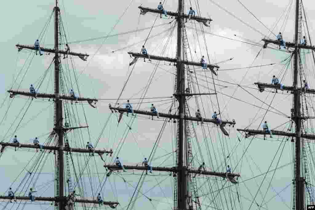 Para mahasiswa Akademi Angkatan Laut Brazil duduk di tiang-tiang kapal pada upacara penyambutan Obor Olimpiade di Rio de Janeiro, Brazil.