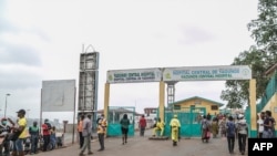 FILE - People walk by the entrance to the Yaounde General Hospital in Yaounde, March 6, 2020, as Cameroon has confirmed its first case of the COVID-19 coronavirus.
