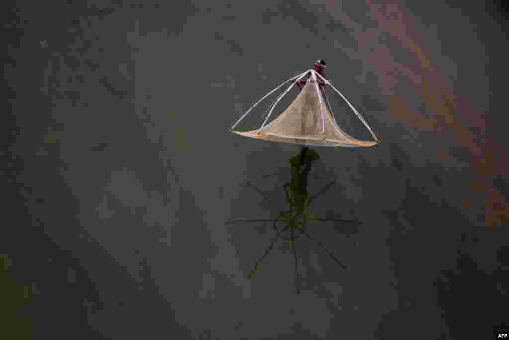 Pria India siap menebarkan jalanya untuk menangkap ikan di Sungai Daya, di pinggiran kota Bhubaneswar.