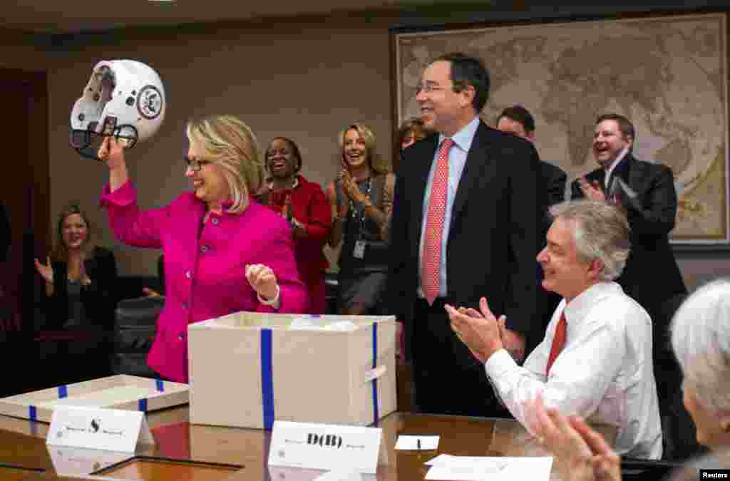 Clinton holds up a football helmet with the State Department logo on it, presented by Deputy Secretary Thomas Nide, who joked that &quot;Washington is a contact sport,&quot; January 7, 2013. 