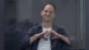 Reporter Wall Street Journal Evan Gershkovich, yang ditahan atas tuduhan spionase, membuat gerakan berbentuk hati di balik dinding kaca saat sidang pengadilan di Moskow, Rusia, 23 April 2024. (Foto: Reuters )