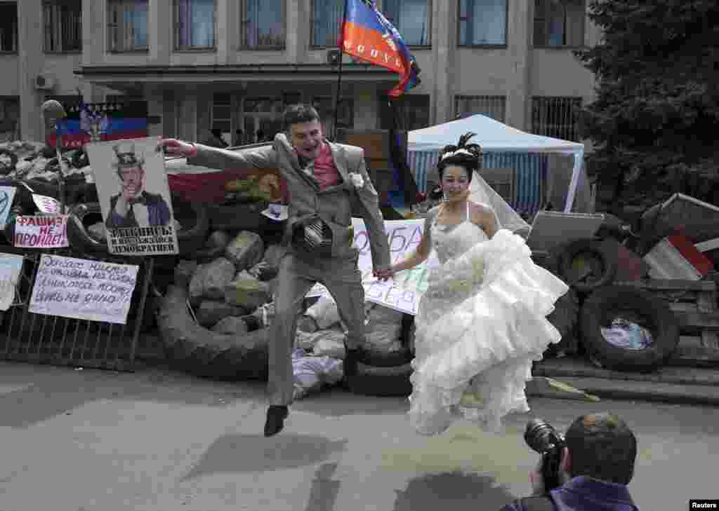 Sepasang pengantin melompat saat sesi foto di depan barikade yang dipasang oleh milisi pro-Rusia di kota Kramatorsk, Ukraina timur.