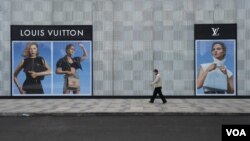 在中国湖北省武汉市，一名男子带着口罩走过法国奢饰品牌路易威登（Louis Vuitton）的一家门店。（2020年2月25日）
