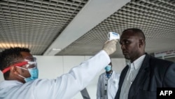 A worker of the Ethiopian Public Health Institute (EPHI) measures a passenger's temperature