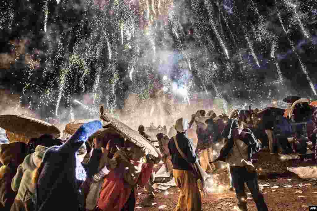 People protecting themselves from fireworks, being carried by a hot air balloon during the Tazaungdaing Lighting Festival at Taunggyi in Myanmar&#39;s northeastern Shan State, Nov. 12, 2016.