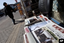 一名北京市民2月16日走过街头报摊，报纸头版刊登中国副主席习近平与奥巴马总统在白宫会晤的照片