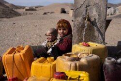 FILE - Watoto wa Afghanistan wakisubiri familia zao kujaza maji katika kijiji cha Kamar Kalagh nje ya mji wa Herat, Nov. 26, 2021.