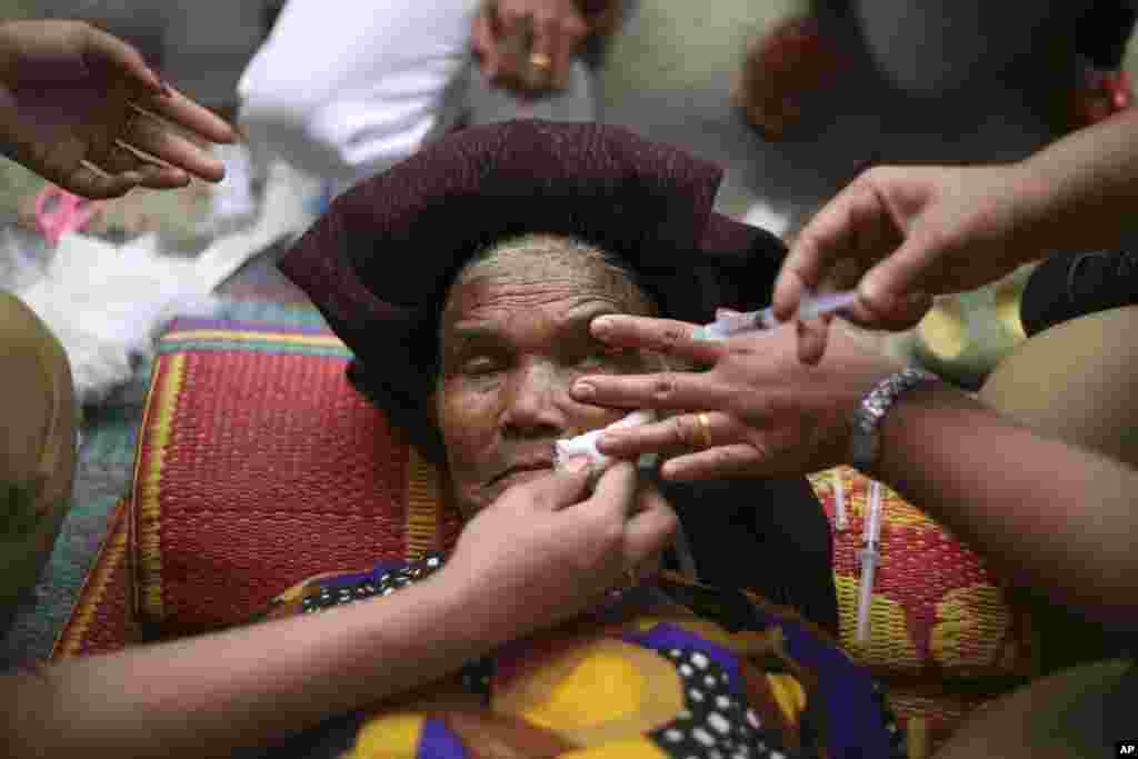 Seorang perempuan lansia menerima pengobatan mata di tempat penampungan sementara bagi warga yang terkena dampak letusan Gunung Sinabung di Kuta Rakyat, Sumatera Utara.