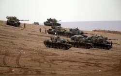 FILE - Turkish soldiers hold their positions with their tanks on a hilltop on the outskirts of Suruc, at the Turkey-Syria border, overlooking Kobani, Syria, during fighting between Syrian Kurds and Islamic State militants, Oct. 12, 2014.