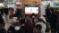 People watch a television screen showing a news broadcast with file footage of a North Korean missile test, at a railway station in Seoul on January 14, 2024.