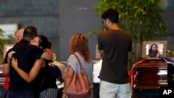People hug beside the coffin of a victim of a collapsed highway bridge, at the Fiera di Genova exhibition where some of the victims are laid in state, in Genoa, Italy, Aug. 17, 2018.